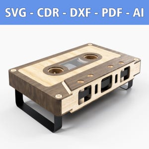 Op de afbeelding: Een houten salontafel in de vorm van een cassettebandje met zwarte metalen poten. De tafel is gemaakt van licht en donker hout en heeft een realistisch cassettebandje-ontwerp.