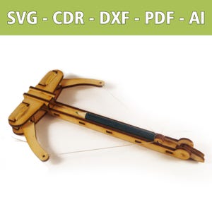 May include: A wooden toy crossbow with a pencil as the arrow. The crossbow is made of light brown wood and has a string for aiming. The top of the image has the text: SVG - CDR - DXF - PDF - AI.