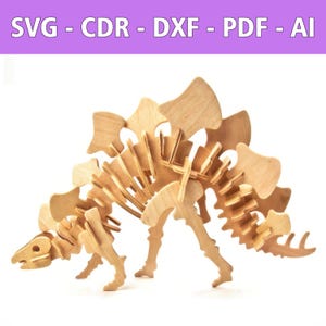 May include: A wooden Stegosaurus puzzle, assembled and standing. The dinosaur is light brown, with a detailed skeletal structure and plates along its back. The image includes the text "SVG - CDR - DXF - PDF - AI" in a purple banner.