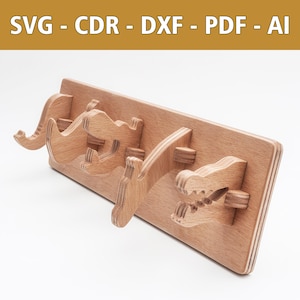 May include: Wooden wall-mounted coat rack with three hooks shaped like animal heads. The hooks are made of light brown wood and have a natural finish. The rack is mounted on a white wall.
