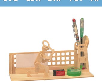 Op de afbeelding: Een bureau-organizer van lichtgekleurd hout met een uitgesneden figuur die een vergrootglas vasthoudt, een achterpaneel met rasterpatroon, een pennenhouder met twee pennen, een kleine rechthoekige gum en een ronde groene houder.