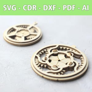 Op de afbeelding: Twee cirkelvormige ornamenten van lichtgekleurd hout met lasergesneden, complexe tandwielpatronen. Bovenaan de afbeelding staat de tekst SVG - CDR - DXF - PDF - AI in witte letters op een lichtgroene achtergrond, wat de digitale bestandsformaten aangeeft.