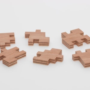 May include: Six wooden puzzle pieces, each with a different shape and layered design. The pieces are made of light brown wood and have a natural finish.