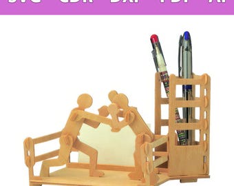 Op de afbeelding: Een bureau-organizer van lichtgekleurd hout met twee gestileerde figuren in een bokshouding, een vierkante pennenhouder en een platte voet. De bovenste banner toont de tekst SVG - CDR - DXF - PDF - AI. Twee pennen zitten in de houder.