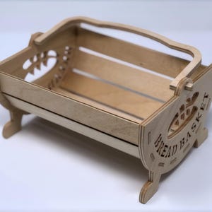 May include: A wooden bread basket with a handle and the words "Bread Basket" carved into the side.