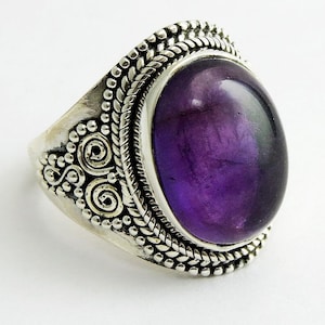 Könnte beinhalten: Ein silberner Ring mit einem verzierten Design und einem großen, ovalen Amethyst-Edelstein.
