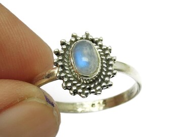 May include: A silver ring with an oval, pale blue moonstone. The moonstone is set in a detailed, textured bezel with a sunburst design. The ring band is a simple, polished silver.