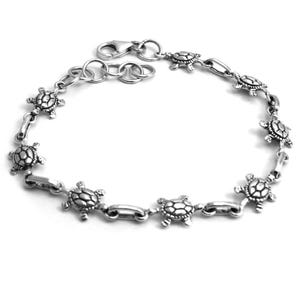 Könnte beinhalten: Silberarmband mit einem Kettenglieddesign und Schildkrötenanhängern.