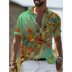 May include: A short-sleeved shirt with a butterfly design. The shirt has a green gradient background and is decorated with butterflies in red, orange, yellow, and blue. It has a relaxed fit and a classic collar. The shirt is buttoned at the front.
