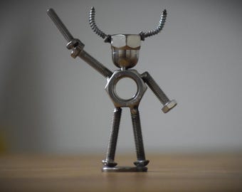 May include: A silver metal sculpture of a bull made from nuts and bolts. The bull has horns, a head, and a body made from metal fasteners.