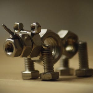 Puede incluir: Una escultura caprichosa de un rinoceronte hecha de varios componentes metálicos. El rinoceronte presenta un tornillo como cuerno, tuercas para los ojos y pernos para las patas, mostrando un estilo de arte industrial único.