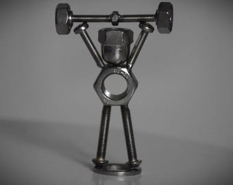 May include: A metal sculpture of a person lifting weights. The sculpture is made of nuts and bolts and is a unique and creative piece of art.