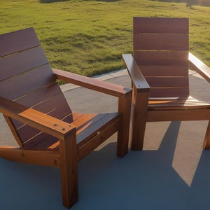 Peut inclure: Deux chaises Adirondack en bois avec une finition en bois naturel. Les chaises sont placées sur un patio en béton avec une zone herbeuse en arrière-plan.