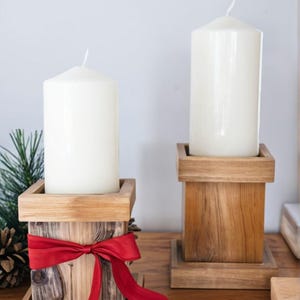 Puede incluir: Dos candelabros de madera con velas blancas. El candelabro de la izquierda tiene una cinta roja atada alrededor.