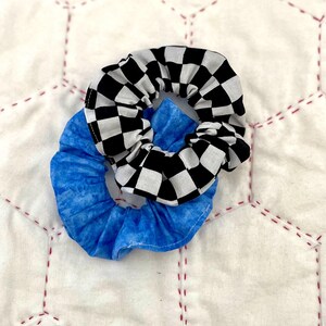 May include: Two fabric scrunchies, one blue with a tie-dye pattern and one black and white checkered.
