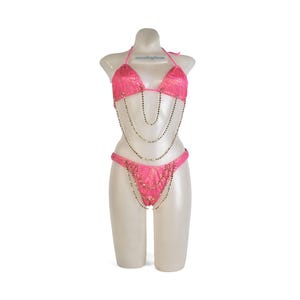 May include: A hot pink bikini set on a mannequin. The top is a triangle style with beaded embellishments and the bottoms are a classic cut. Silver-colored chains hang from the top and bottom, adding a touch of glamour.