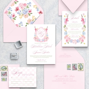 Pode incluir: Um conjunto de papelaria de casamento com envelopes rosa claro com forros de padrão floral, um convite principal com um brasão floral rosa, um cartão de detalhes e um cartão RSVP. Inclui um anel de prata numa caixa e três selos postais.