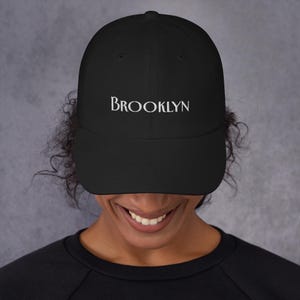 May include: A black baseball cap with a white embroidered word "BROOKLYN" on the front.