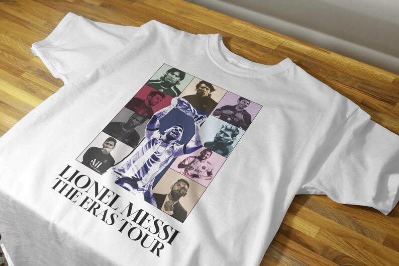May include: White t-shirt featuring a collage of Lionel Messi images in various poses and eras. The shirt includes the text "Lionel Messi The Eras Tour" in a bold, black font, suitable for fans.