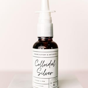 Könnte beinhalten: Eine braune Glasflasche mit kolloidalem Silber und einem weißen Sprühkopf. Das Etikett lautet "Immune Support & Antiseptic" und "Colloidal Silver". Die Flasche enthält etwa 118 Gramm.