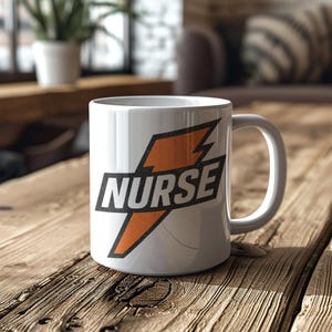May include: White ceramic mug featuring a black and orange lightning bolt design and the word "NURSE" in a bold, black font. The mug is placed on a wooden surface. The mug has a handle on the right side.