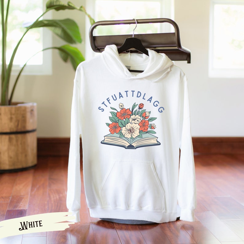 May include: White hooded sweatshirt with a graphic of a book with flowers on top and the text "STFUATTDLAGG" around the book.