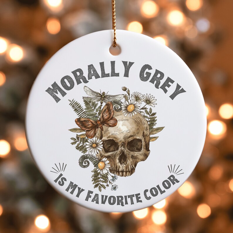 Puede incluir: Adorno de cer&aacute;mica blanca con una calavera rodeada de flores y una lib&eacute;lula. El texto "Morally Grey is my favorite color" est&aacute; impreso en el adorno.