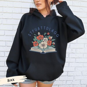May include: Black hooded sweatshirt with a floral design and the text "STFUATTDLAGG" printed on the front.