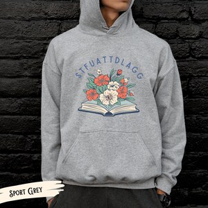 May include: A gray hooded sweatshirt with a floral design and the text "STFUATTDLAGG" printed on the front.