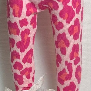 May include: Pink and orange leopard print leggings with white shoes. The shoes have white laces and a white bow on the front.