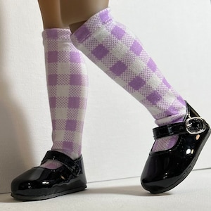 May include: A pair of black patent leather shoes with a buckle closure. The shoes are worn with white and lavender checkered knee-high socks.