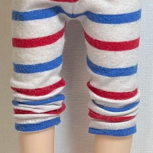 May include: Red, white, and blue striped leggings for a doll. The leggings are made of a soft, stretchy fabric and have a comfortable fit.