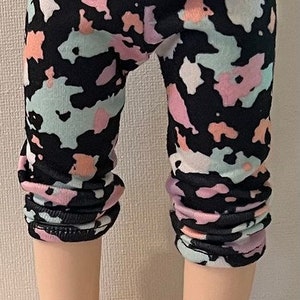 May include: Black leggings with a colorful abstract print in shades of pink, blue, and white.