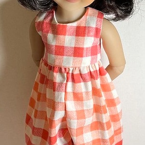 May include: A doll with black hair wearing a red and white gingham jumpsuit and white sneakers. The doll is wearing a red and white gingham bow in her hair.