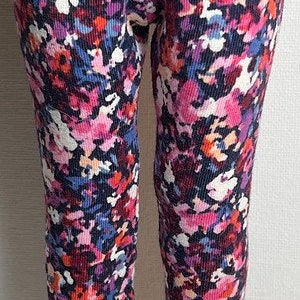 May include: A pair of floral leggings with a dark blue background and pink, white, and red flowers. The leggings are made of a soft, stretchy fabric.