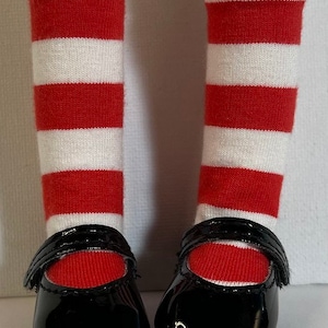 May include: A pair of black patent leather shoes with a strap across the top. The shoes are worn with red and white striped knee-high socks.