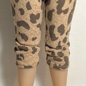 May include: Brown and tan leggings with a leopard print pattern. The leggings are on a doll with white sneakers.