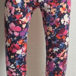 May include: A pair of black patent leather shoes with a strap across the top. The shoes are worn with pink, blue, and orange floral leggings.