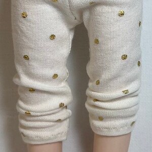 May include: White leggings with gold polka dots. The leggings are made of a soft, stretchy material and have a ribbed texture.