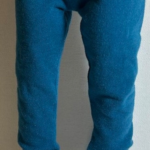May include: A pair of blue leggings with white sneakers. The sneakers have white laces and a black trim around the sole.