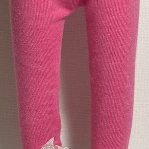May include: Pink leggings with white shoes and white ribbon accents. The shoes have a textured sole.