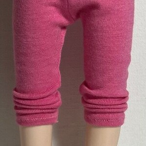 May include: Pink leggings for a doll, with a cuffed hem.