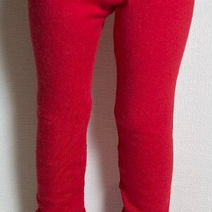 May include: Red leggings with white sneakers. The leggings are a solid, vibrant red color and appear to be made of a ribbed knit fabric. The white sneakers have white laces and a black trim.