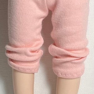 May include: A pair of pink knit leggings for a doll. The leggings are made of a soft, stretchy fabric and have a ribbed texture.