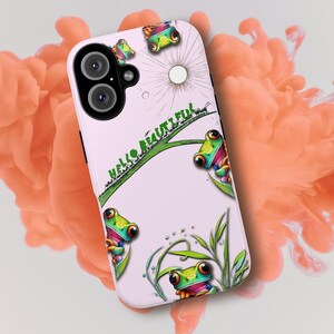 May include: A pink phone case with a white background and a green and orange frog design. The case has the text "Hello Beautiful" printed on it.