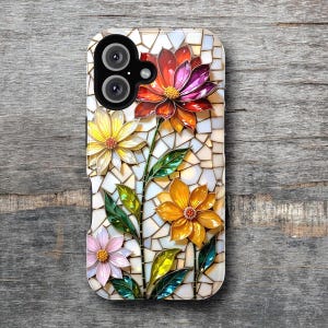 May include: A phone case featuring a mosaic floral design. The case has a white background with a mosaic pattern. Colorful flowers in shades of red, orange, yellow, and pink are arranged on the case, with green leaves and stems.