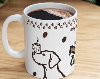 May include: White ceramic coffee mug filled with dark coffee. The mug features a black and brown paw print pattern, coffee beans, and a dog illustration. Text on the mug reads "only my balance is coffee".