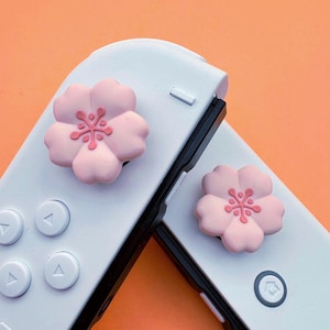 Poignées pour le pouce - Nintendo Switch/OLED - Fleurs de sakura roses - Paire d'embouts de pouce sakura épais et confortables de haute qualité (Joycons non inclus)