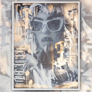 May include: A framed abstract art print with a black and white image of a person wearing sunglasses. The background is a mix of gold, white, and black paint splatters and textures.