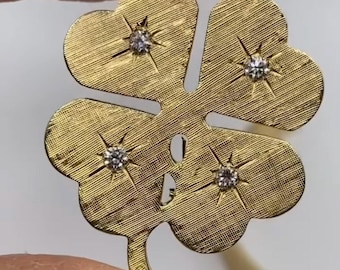 May include: A gold four-leaf clover pendant with four small diamonds set in the center of each leaf.
